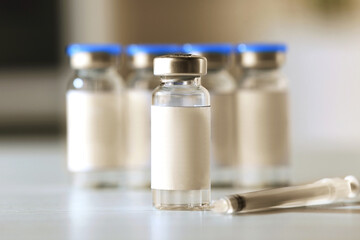 Medication in vials and syringe on table, space for text