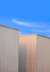 Fototapeta na wymiar Part of two Corrugated Metal Industrial Warehouse Buildings against blue sky Background, Perspective side view and Vertical frame