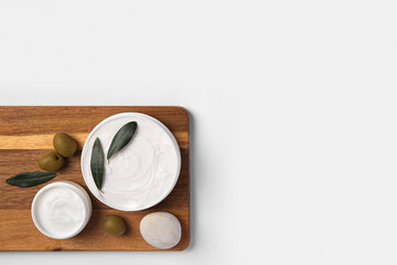Jars of cream with olives and stone on white background, top view. Space for text