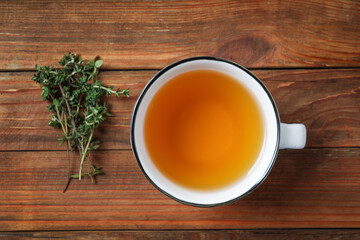 Aromatic herbal tea with thyme on wooden table, flat lay