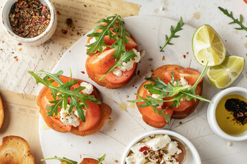 Bruschetta with tomatoes, arugula, olive oil and cheese on plate on textured background. Fresh italian toasts top view