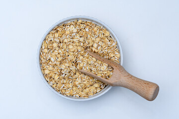 Płatki owsiane w białej misce z drewnianym nabierakiem 