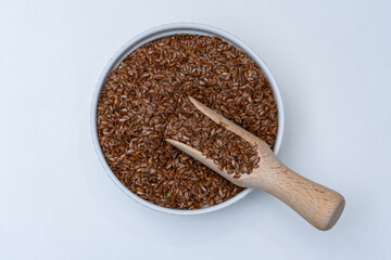 Brązowe siemię lniane w okrągłej miseczce z nabierkiem wypełnionym nasionami 