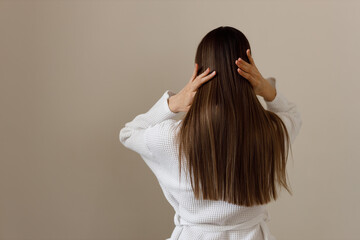 Young woman with healthy long smooth hair in white bathrobe, rear view. Hygiene, freshness,...