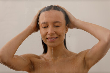 Young woman under trickles water in pleasure shower. Beautiful girl under spray of water on...