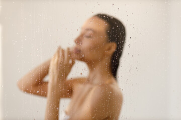 Young woman under the trickles of water in pleasure shower. Beautiful girl under the spray of...