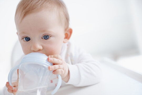 No more bottles for the big boy. Cropped image a cute baby boy drinking from his sippy cup.