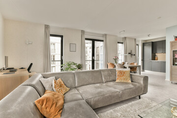 a living room with couches, coffee table, and tv in the center of the room is large windows