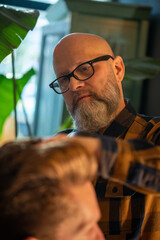 Bearded male barber cutting hair of a client in a barbershop. High quality photo