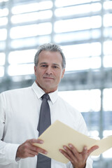 Fototapeta premium Year end figures. Portrait of a mature businessman looking at a file in the office.