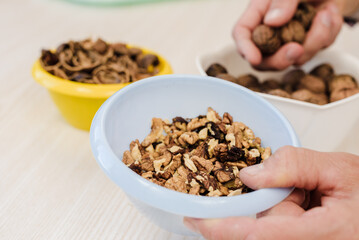 Young unrecognizable man peeling walnuts at home, closeup photo