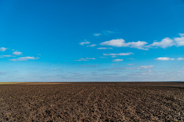 View to spring landscape in sunny day with an agricultural plowed field and blue sky. Natural background