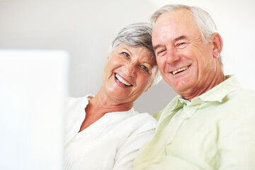 Smiling mature couple using laptop at home. Portrait smiling mature couple using laptop while sitting on couch.