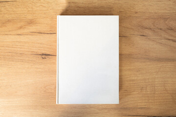 white book with an empty pesto for text and design on a wooden background