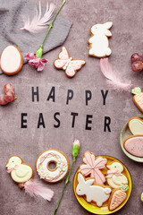 Easter glazing cookies, feathers, aster flowers flat. lay Happy Easter text. Spring stylish background