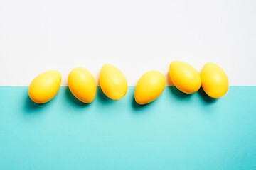 Yellow Easter eggs on white and blue background. Top view, flat lay, copy space
