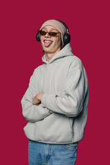 Portrait of young handsome funny funky man wearing sunglassesand headphones listening music isolated on pink background studio. People lifestyle concept
