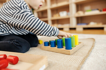 A little boy is learning ordering by size educational toy in kindergarten.