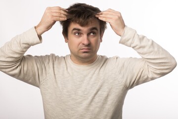 a European man holds his hair with his hands. I need a haircut