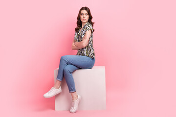 Full length portrait of capricious person sit cube podium crossed arms look empty space isolated on pink color background - obrazy, fototapety, plakaty