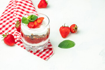 strawberry parfaits with fresh fruit, yogurt and granola on white table, glass jar. Healthy breakfast. Long banner format. top view