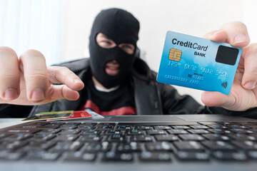 Man in robber mask uses internet, bank account and credit facilities. Phishing attack by male with...