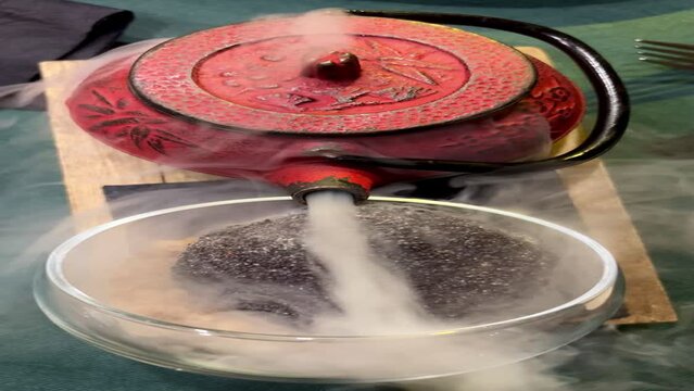 vertical video of a kettle with liquid nitrogen vaporizing black truffle ice cream
