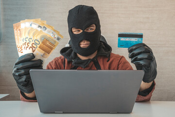 stealing money via the Internet is a concept. credit card fraud. Happy cybercriminal man holding euro cash and stolen credit card