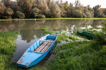 Panorama of an abandoned rowing boat, an blue small boat, resting in the neglected shore of the tamis timis river in Jabuka, in Vojvodina, Serbia, in central Europe