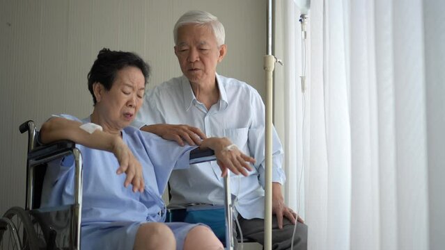 Asian senior couple husband talk to accident injured wife in wheelchair health care hospital treatment