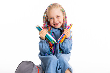 Schoolgirl adorable kid with colorful braids holding pencils in hands sitting on white floor in...