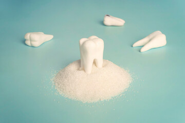 Tooth with sugar on blue background. Harm of sugar and sweet for teeth, care. concept, tooth loss
