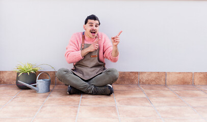 young handsome man gardering and sitting on the floor outdoors
