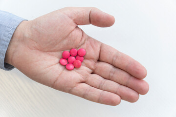 red pills in a man hand close-up. the concept of treatment. antiviral agent. top view