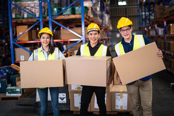 Asian warehouse workers team hold cardboard box packaging in warehouse distribution center environment. teamwork at warehouse storage department.