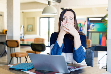 young pretty woman covering mouth with hands with a shocked. telecommuting concept