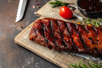 hot grilled spare ribs on cutting board on a dark background. American Spare Ribs in BBQ Sauce. Restaurant menu, dieting, cookbook recipe top view