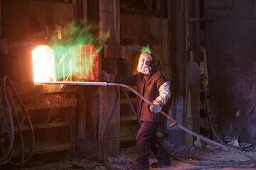 Man stands near an open gas furnace in a copper factory.