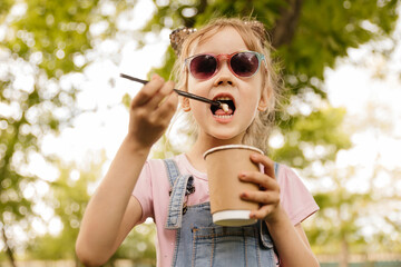 little girl drinking cocoa in the summer in the park