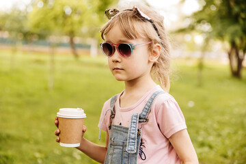 little girl drinking cocoa in the summer in the park wearing a cat ear headband