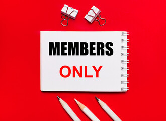 White notebook with MEMBERS ONLY text, white pencils and paper clips on a bright red background