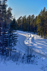 View of a slippery winter road on the Swedish country side, snow and ice hanging from the trees.