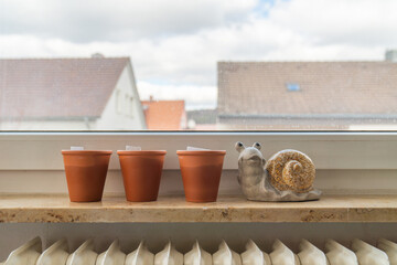Three terracotta pots on the windowsill with the figure of a snail