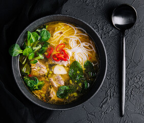 Chicken soup with vegetables in black bowl