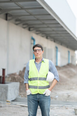 Fototapeta premium Portrait of a Professional American Heavy Industry Engineer Wearing Safety Uniform, Glasses, Hard Hat, Looking into the Camera. Confident American Industrial Specialist Standing in a Factory Facility