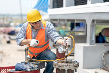 Mechanical maintenance technician inspecting pressure gauge of heating system in heating plant.