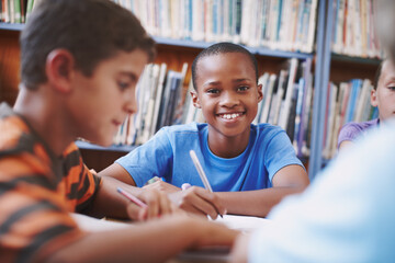 Im going to be a journalist one day. An african american boy sitting in the library and working with his classmates.