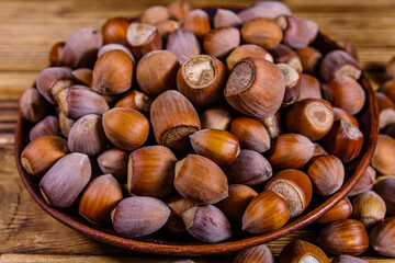 Plate with pile of hazelnuts on a wooden table