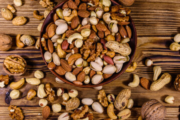 Various nuts (almond, cashew, hazelnut, pistachio, walnut) in ceramic plate on a wooden table. Vegetarian meal. Healthy eating concept. Top view