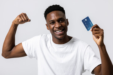 Portrait of african young student guy celebrating smiling holding new credit card advertisement of...